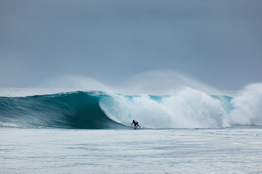 Surfer riding a powerful ocean wave under stormy sky