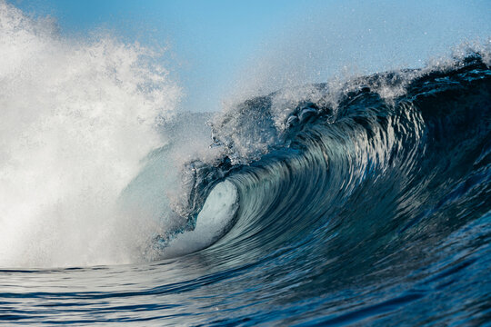 Powerful ocean wave curling with white spray and blue water