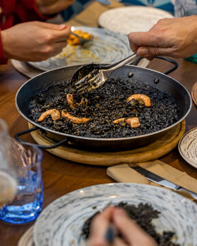 Spanish black rice seafood paella served at dinner table