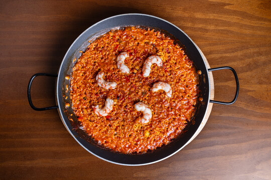 Spanish seafood rice in pan on wooden table, top view