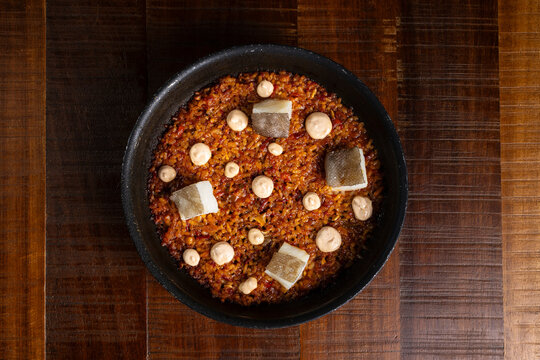 Spanish rice in paella pan with cod and aioli sauce