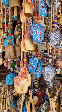 Vertical 4k video of hand painted Greek goat bells and wooden marine decor in Spili, Crete. Close up of traditional colorful bells and nautical handicrafts in local souvenir shop. Artisan art.
