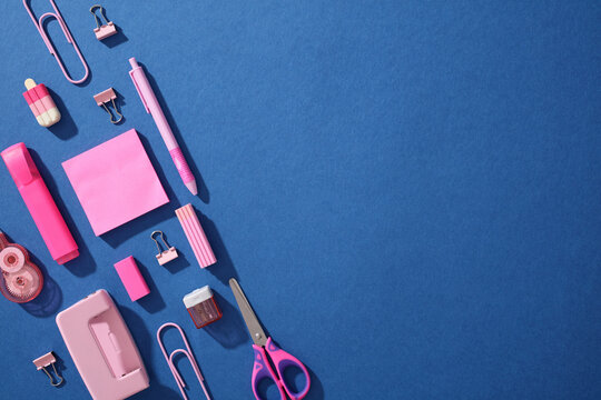 Pop art flat lay of pink school supplies on blue background
