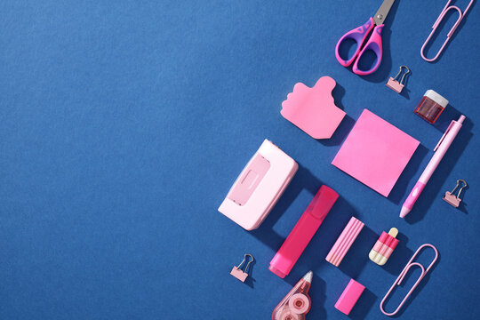 Pop art flat lay of pink school supplies on blue background