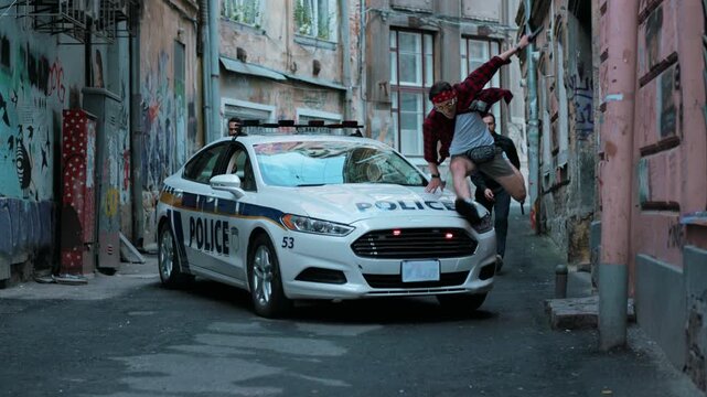 The offender escapes from the police criminal street near patrol car burglar crime hold danger gangster gun robber uniform illegal law bad guy close up slow motion