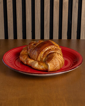 Golden croissant on red plate for morning breakfast