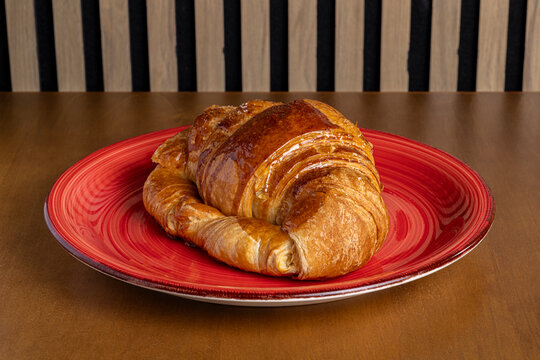 Golden croissant on red plate for morning breakfast