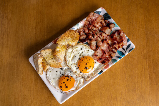 Hearty breakfast plate with fried eggs, bacon and toast