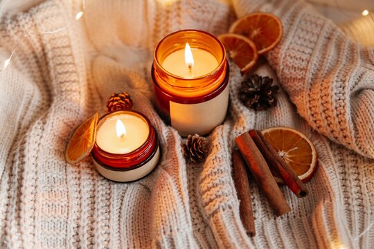 Cozy soy candles with orange and cinnamon on knit