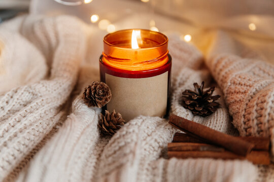 Cozy scented candle with pinecone and cinnamon on knit