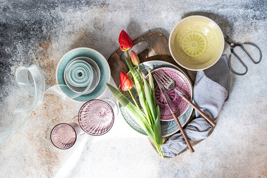 Red tulips on rustic table with colorful dishes flat lay