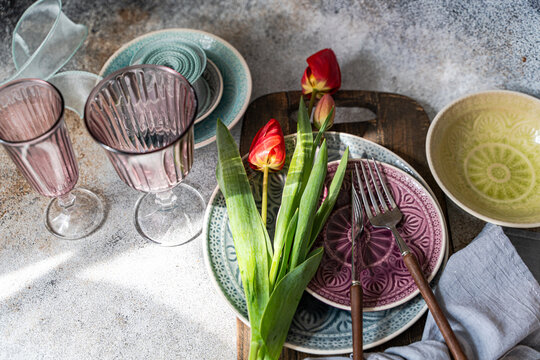 Red tulips on table set with plates, glasses and cutlery