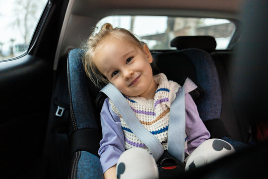 Child in car seat wearing seat belt on family trip