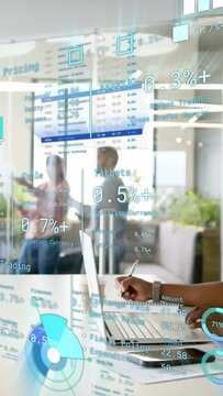 Vertical video: Seated woman typing and writing starting finance AR charts on glass for review
