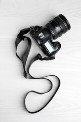 Obraz premium Modern camera with strap on white wooden table, top view