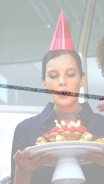 Vertical video: Woman lifting cake, team helping, blowing candles for work birthday, balloons