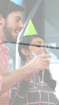 Vertical video: Pair of staff clinking flutes in office, toasting on cue and releasing confetti