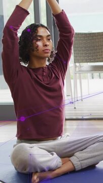 Vertical video: Yogi with arms up lowering to prayer on blue mat purple overlay moving for wellness