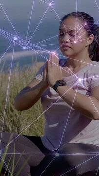Vertical video: Woman pressing palms on dune holding prayer as network mirroring breath for health
