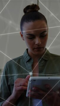 Vertical video: Woman with white tablet tapping screen reading IT data as network nodes animating