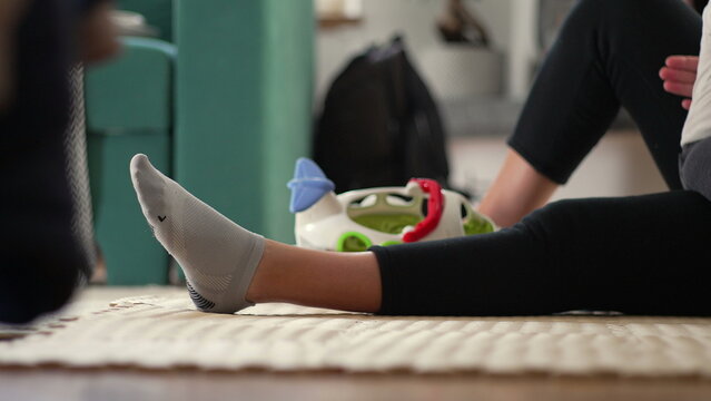 Woman sitting on floor near child&rsquo;s toy airplane inside cozy living room, relaxed moment of motherhood and domestic calm, everyday family life at home with toddler playtime