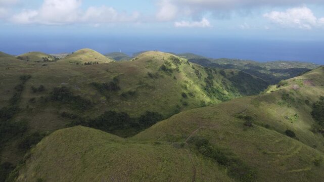 Cinematic aerial drone hovering above the lush landscape of Teletubbies Hill, Nusa Penida, Indonesia.