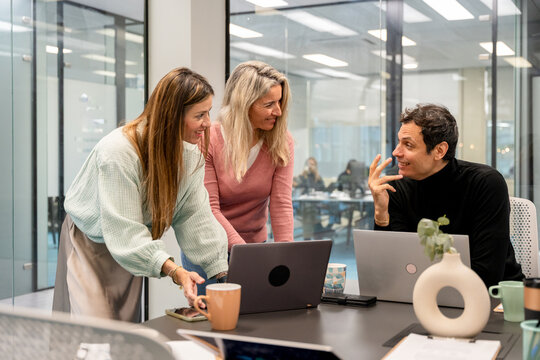 Coworking team discussing project around laptop in office
