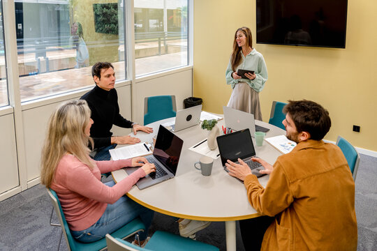 Coworking team meeting in office with laptop and tablet