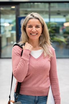Smiling businesswoman with bag in coworking office lobby