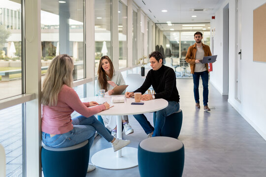 Modern coworking team meeting at table in office hallway