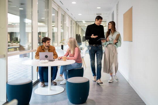 Coworking team discussion in bright modern office hallway