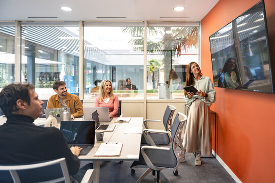 Coworking team meeting with presentation on office screen