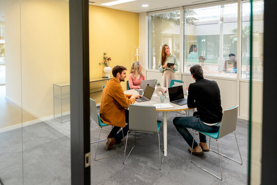 Coworking team meeting in modern office with laptop and tablet
