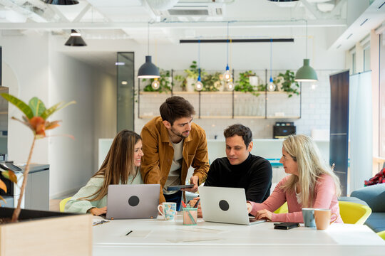 Coworking team meeting around laptop in modern office space