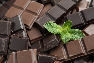 Pieces of yummy chocolate and mint leaves as background, closeup © New Africa