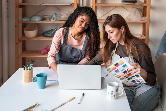 Women planning pottery workshop  with laptop and color palette