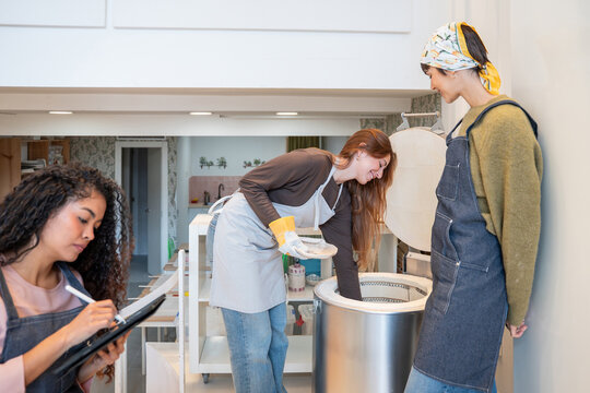 Potter removing ceramic piece from kiln during workshop