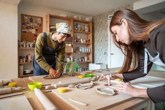 Pottery workshop with artisan shaping clay at studio table