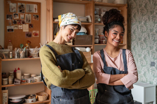 Two smiling potters posing in a cozy pottery workshop