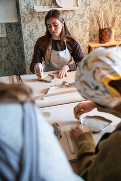 Young woman shaping clay slab during pottery workshop class