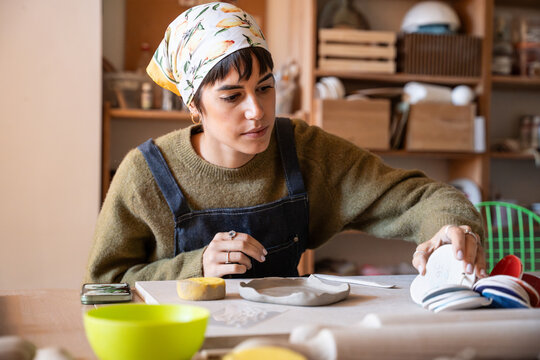 Potter shaping ceramic plate in cozy pottery workshop