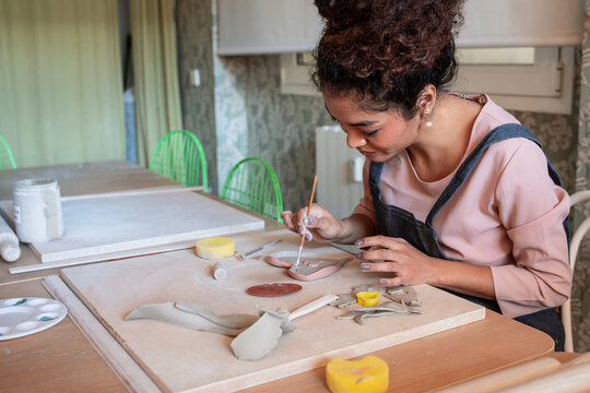 Young woman shaping clay pieces at a pottery workshop table