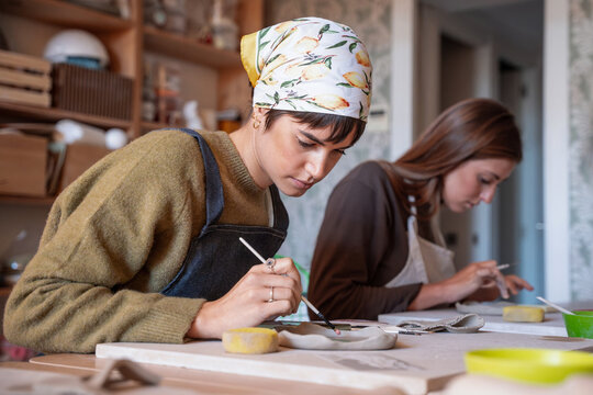 Artists painting ceramic piece in a pottery workshop studio