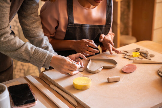Hands shaping clay in pottery workshop with tools on table