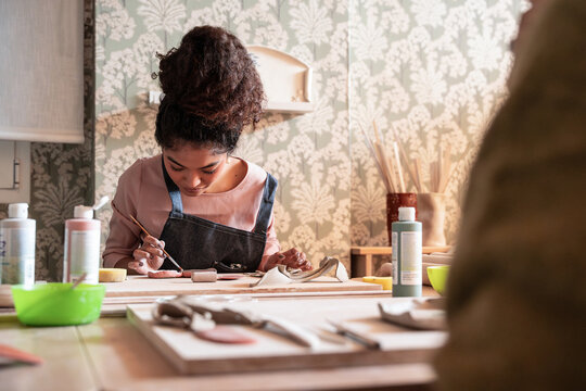 Pottery workshop artisan painting clay pieces at a table
