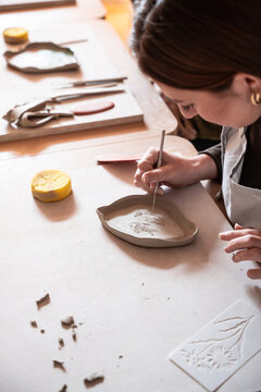 Potter carving a clay dish during a pottery workshop