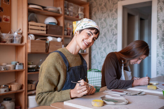 Smiling artisan in pottery workshop shaping ceramic clay