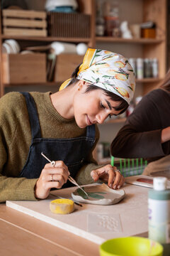 Ceramic artist painting clay plate in pottery workshop studio