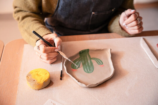 Person painting a handmade ceramic plate in pottery workshop