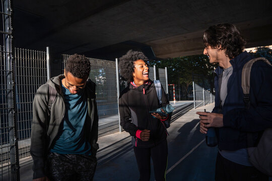 Group of friend laughing outdoors under urban overpass